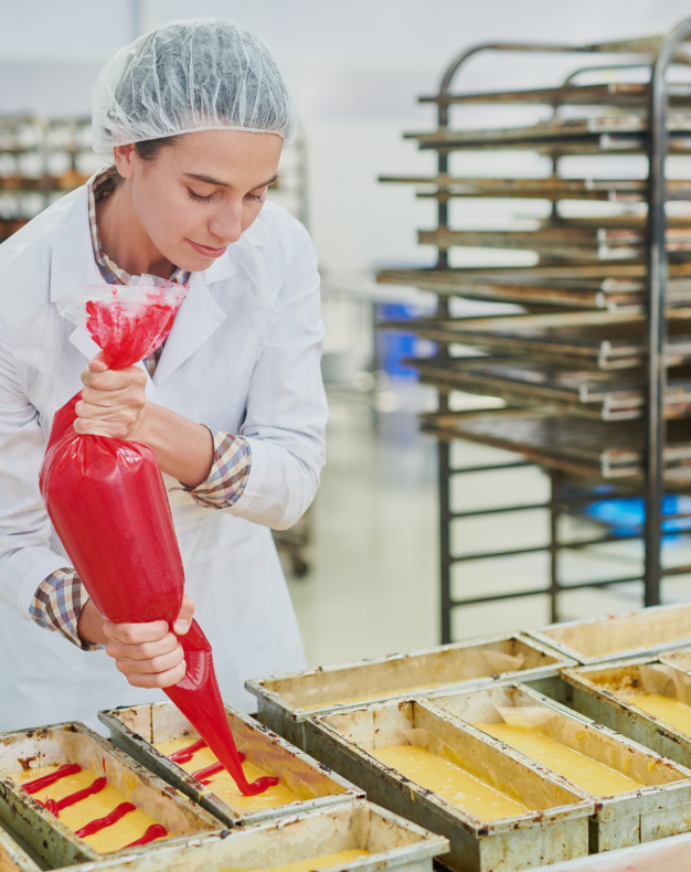 Confectionery factory employee using pastry bag