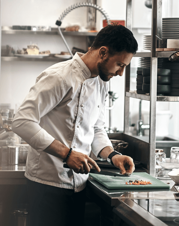 A chef in the kitchen cutting